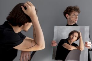 A young man with drawn lines on his face looks at his reflection in a mirror, symbolizing identity confusion or distorted self-perception