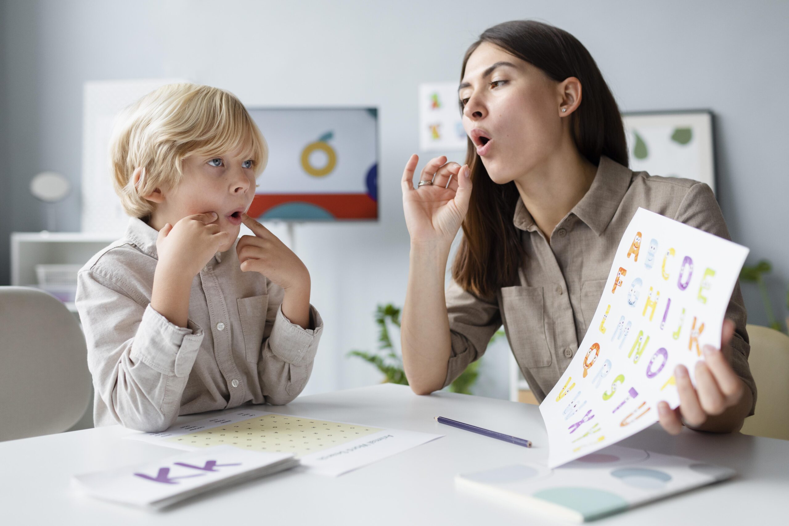 Speech therapist teaching a young boy pronunciation using alphabet cards during a language therapy session.